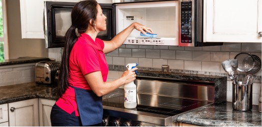 woman cleaning inside of microwave